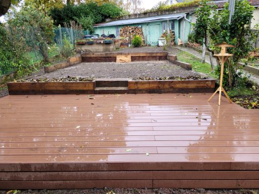 Terrassement de paliers plats sur un jardin en pente grâce à des retenues de terre en traverse de chêne brut et une terrasse composite